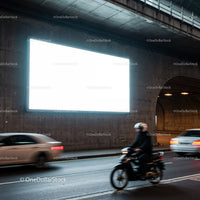 Motorcyclist and cars passing by illuminated billboard