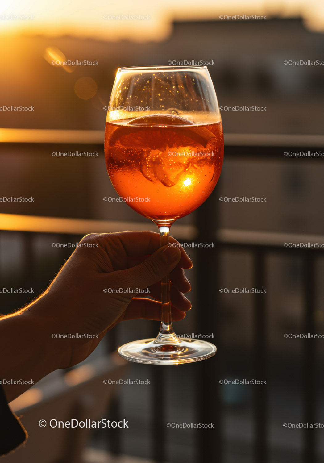 Dłoń trzymająca Aperol Spritz na tle złotego światła zachodzącego słońca