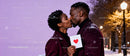 Affectionate couple kissing with Valentine card outdoors