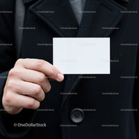 Hand holding blank white business card on black coat