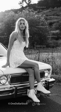 Young woman in white dress sitting on vintage car with roller skates