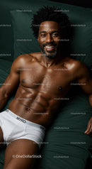 Smiling muscular man relaxing on dark green bedding
