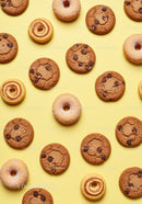Assorted chocolate chip cookies and mini donuts on yellow background