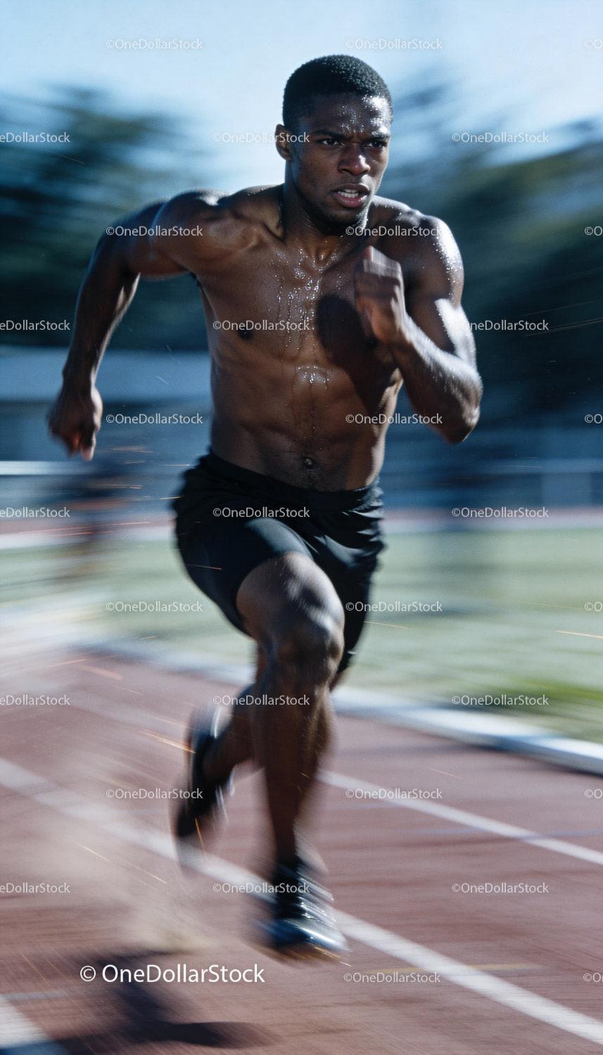 Focused male sprinter running at full speed on track
