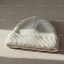 Soft White Knitted Beanie Hat on Neutral Fabric