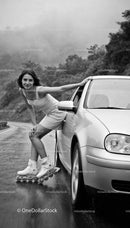 Young woman rollerblading while holding car door on rainy road