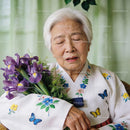 Elderly woman in traditional dress holding purple irises