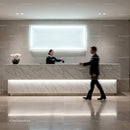 Hotel receptionist handing key card to guest at marble desk