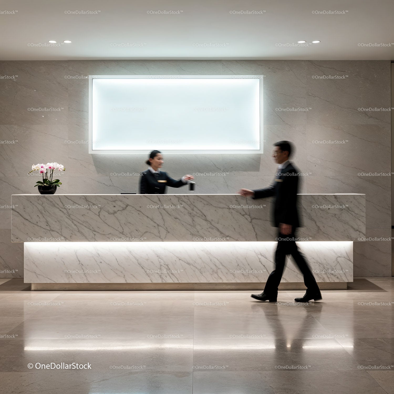 Hotel receptionist handing key card to guest at marble desk