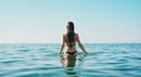 Woman in Black Bikini Swimming in Calm Blue Ocean Under Clear Sky