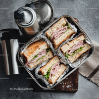 Ham and Lettuce Sandwiches in Aluminum Foil with Thermos on Brown Wooden Surface