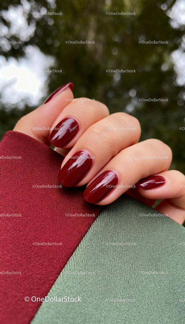 Zbliżenie na dłoń z błyszczącym, ciemnoczerwonym manicure