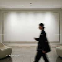 Blurred figure walking past blank white gallery wall