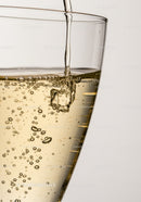 Golden sparkling wine pouring into glass with bubbles