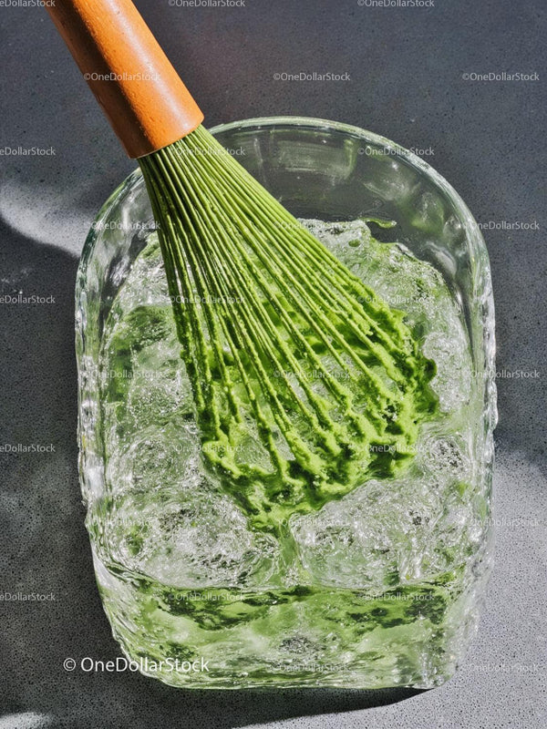 Green matcha whisk immersed in refreshing ice water