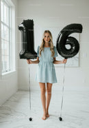 Teenage girl celebrating sixteenth birthday with balloons