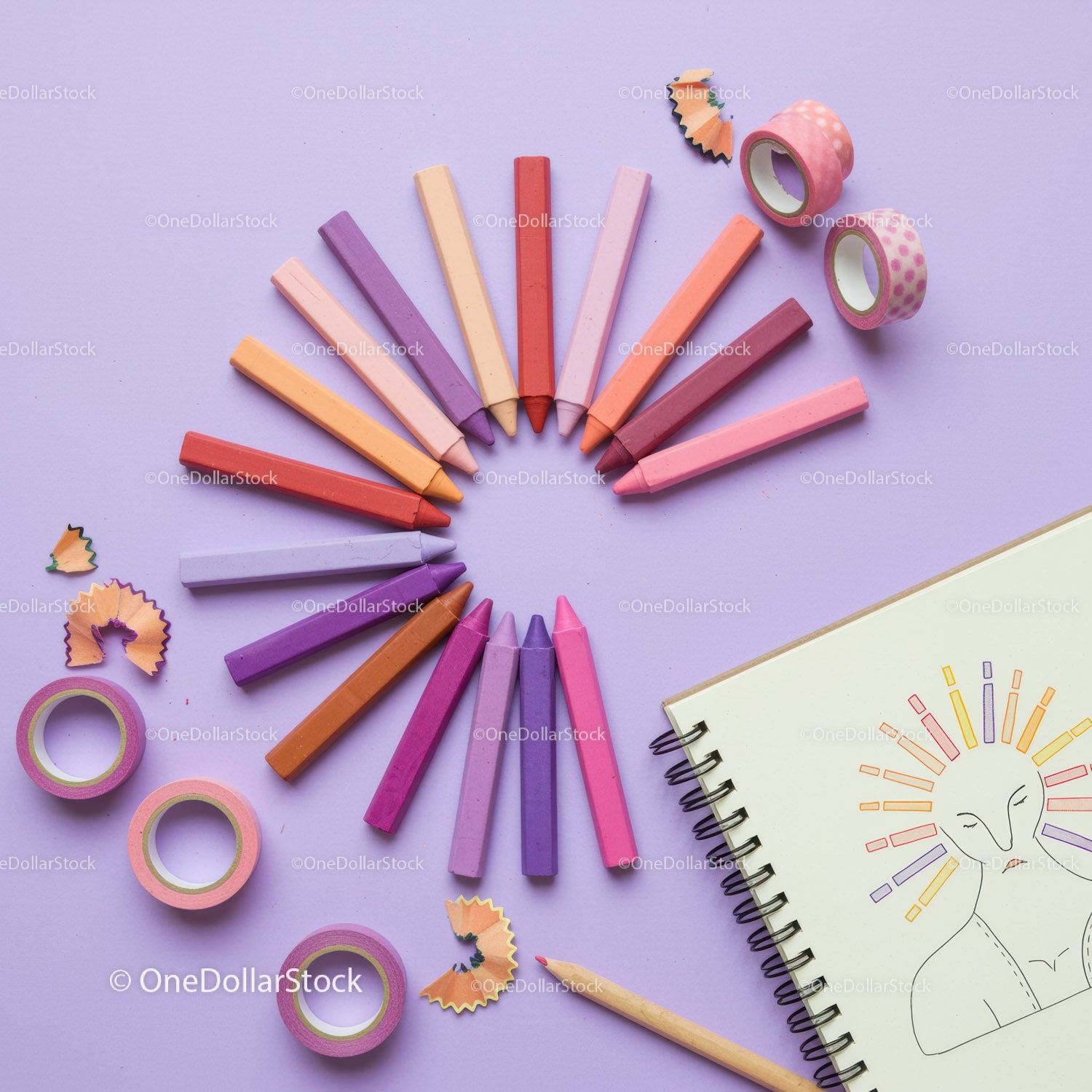 Colorful pastel chalks arranged in a circular pattern with sketchbook