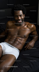 Smiling muscular man relaxing on black bedding in white underwear