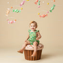 Toddler girl sitting on giant cupcake with candy mobile