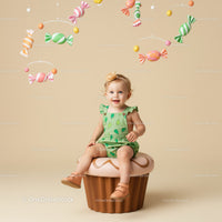 Toddler girl sitting on giant cupcake with candy mobile
