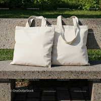 Two Blank Canvas Tote Bags on Outdoor Stone Bench