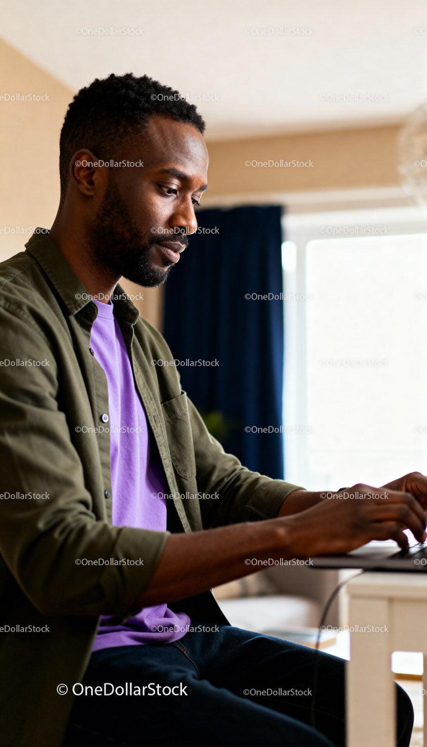 Focused young man working on laptop at home desk