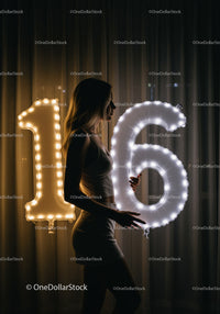Young Woman Holding Illuminated Number Balloons Sixteen