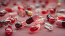 Red and Transparent Capsules with Gel Coating on Pink Background