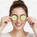 Bright Smiling Woman Holding Cucumber Slices Over Eyes for Skincare