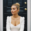 Thoughtful young woman in white dress by black door