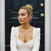 Thoughtful young woman in white dress by black door