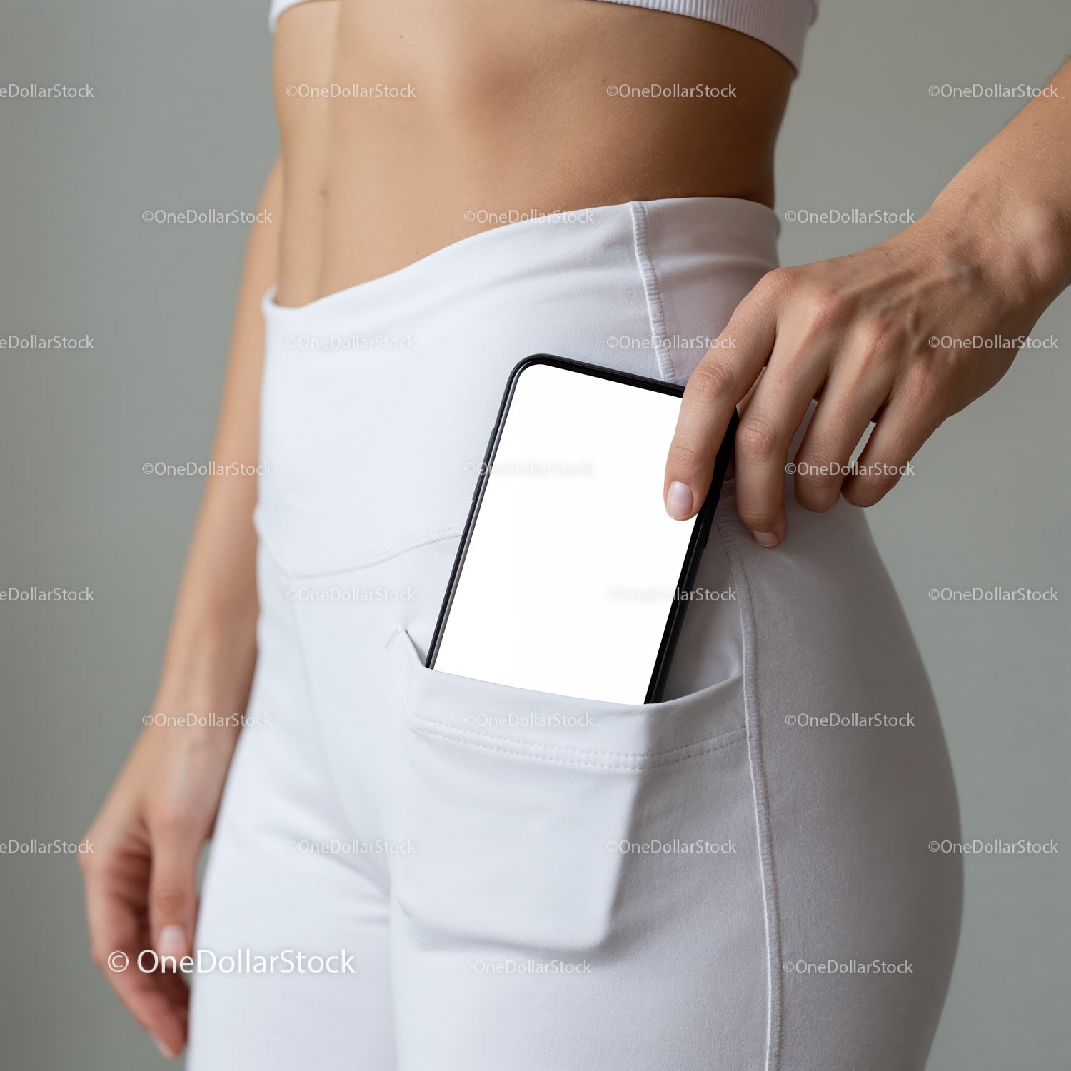 Kobieta wkłada smartfon do kieszeni białych spodni z wysokim stanem