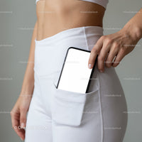 Woman placing smartphone in white high-waist pants pocket