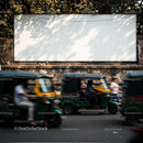 Busy street scene with moving auto rickshaws and blank billboard