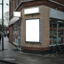 Empty illuminated billboard on urban corner store facade