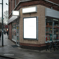 Empty illuminated billboard on urban corner store facade