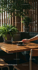 Hand Holding Coffee Cup in a Cozy Cafe Surrounded by Plants