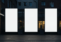 Empty illuminated billboards on urban street at dusk
