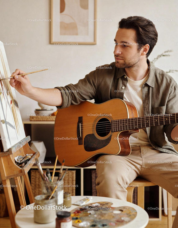 Man playing guitar while painting art on canvas