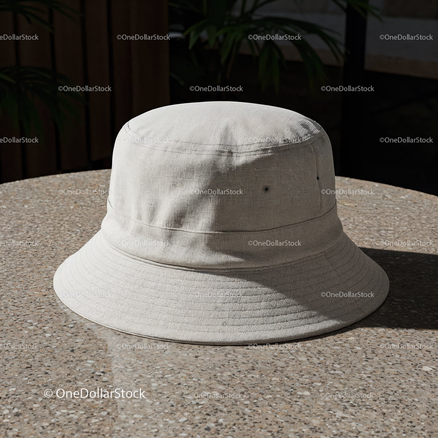 Minimalistyczny beżowy kapelusz typu bucket na okrągłym, teksturowanym stole