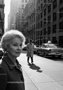 Elderly Woman in Busy City Street Surrounded by Vintage Cars