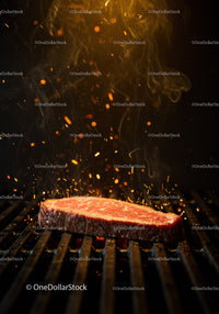 Fresh steak sizzles on hot grill with glowing sparks