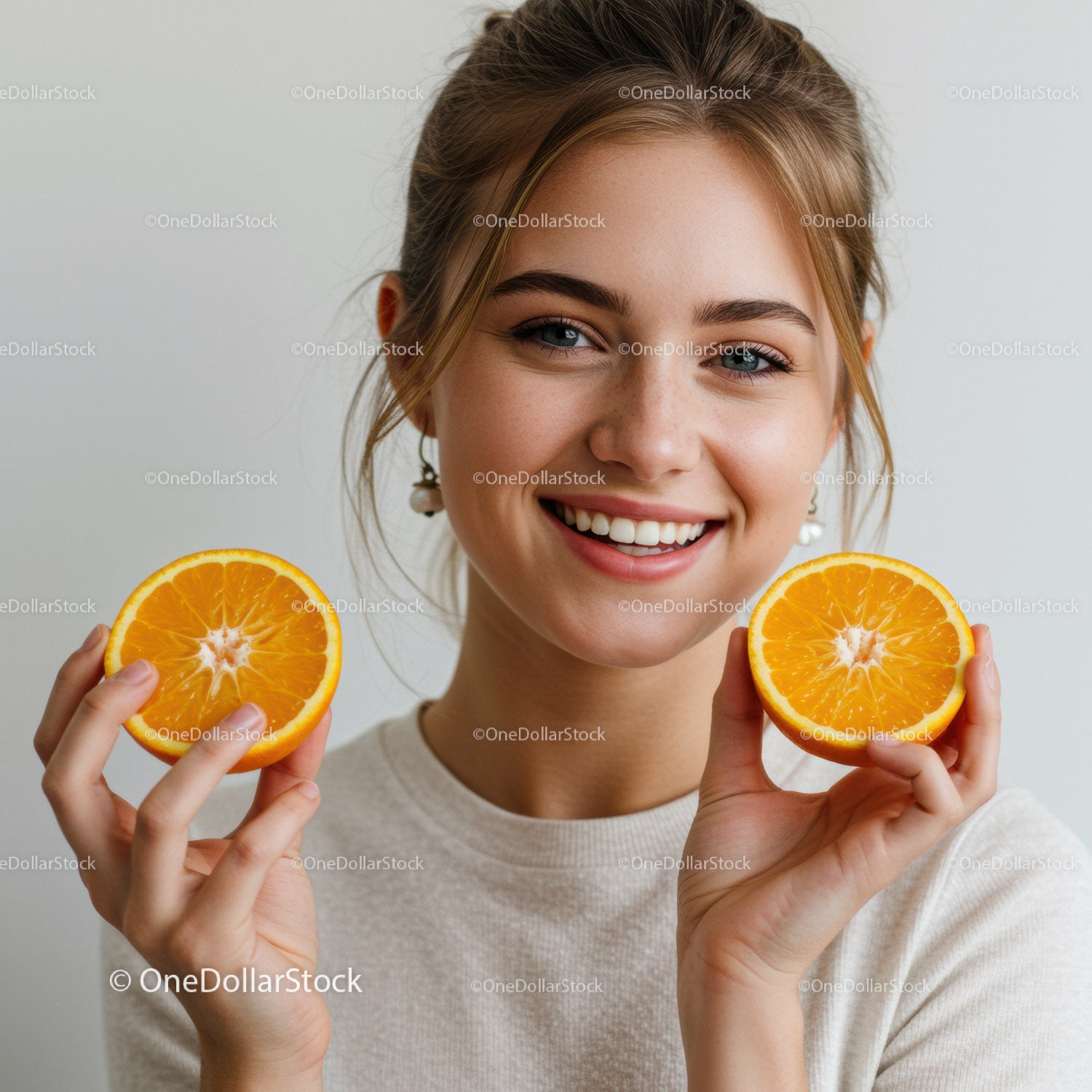 Beautiful Young Woman Holding Fresh Orange Halves in Bright Studio
