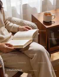 Relaxed woman reading book with steaming tea nearby