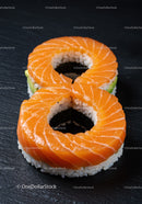 Two salmon sushi rolls shaped like number eight on black slate