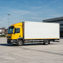 Yellow delivery truck parked in empty urban plaza