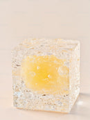 Transparent cube with vibrant yellow core on neutral background