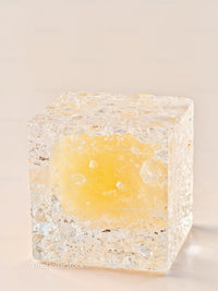 Transparent cube with vibrant yellow core on neutral background