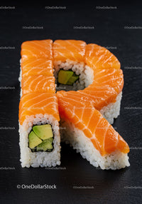 Fresh salmon sushi rolls shaped as letter R on black plate