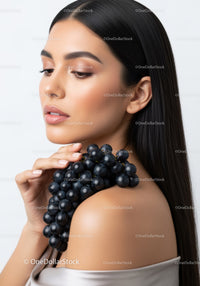 Elegant Woman with Flawless Skin Holding Grapes in Soft Light